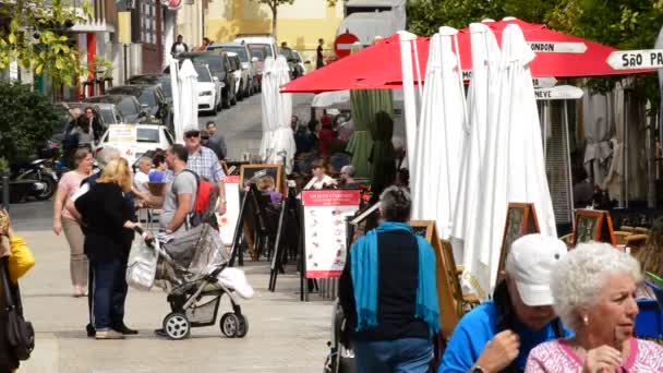 Turister och människor som gick en solig morgon vid en gata med terrasser och barer i Málaga, Andalusien, Spanien — Stockvideo