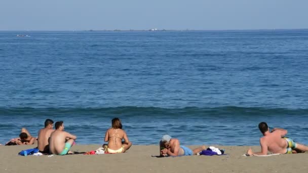 Jovens banhos de sol na praia uma tarde ensolarada em Málaga, Espanha — Vídeo de Stock