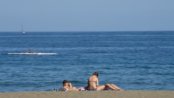 ピローグやビーチでの日光浴の人と一緒に海で行くカヌー — ストック動画
