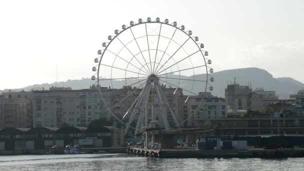 Reuzenrad spinnen met gebouwen van een stad bij zonsondergang in Malaga, Spanje — Stockvideo