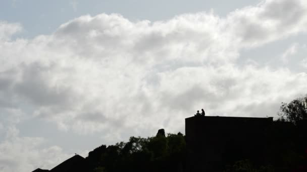 Twee meisjes op de top van een kasteel muur backlit praten en drinken een bewolkt middag in La Alcazaba, Malaga, Spanje — Stockvideo