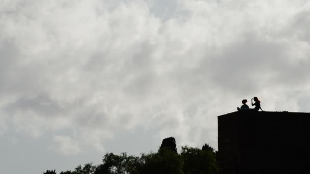 Meninas no topo de uma parede do castelo no backlit . — Vídeo de Stock