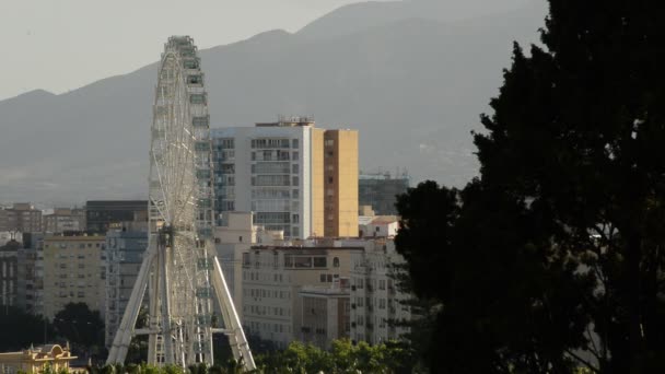 Riesenrad dreht sich mit Gebäuden einer Stadt bei Sonnenuntergang — Stockvideo