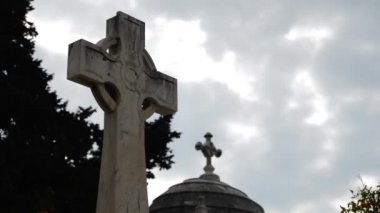 Bulutlu bir günde mezarlıkta taş kesişiyor.