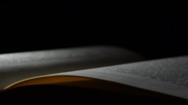 Siyah arkaplan ile dönen açık bir kitaptan bahseden sayfalar