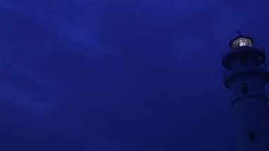 Gün batımında deniz feneri ışık sinyalleri gönderiyor.