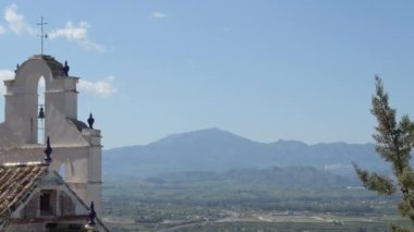Antik bir inzivanın çan kulesi gün batımında dağlara bakıyor.