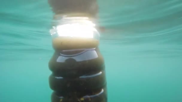日没時に海底に浮遊する未舗装のペットボトル スローモーション — ストック動画