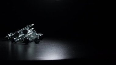 Siyah arka planda dönen endüstriyel metal vidalar.
