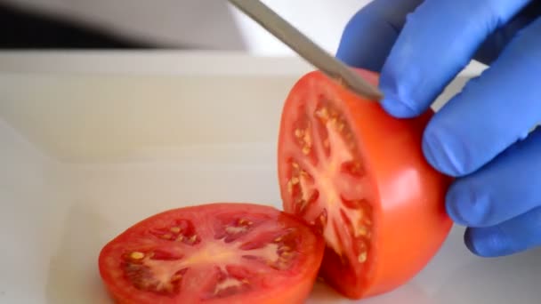 Chef-kok handen snijden een tomaat — Stockvideo