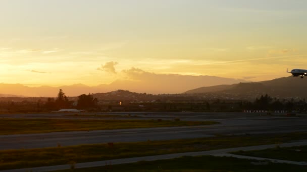 Vliegtuig vliegen naar de luchthaven bij zonsondergang — Stockvideo