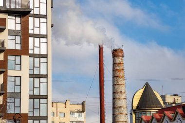 Şehrin arka planında, termal kazan dairesinin bacasından çıkan beyaz duman. Ekoloji sorunları. Isıtma sezonu.