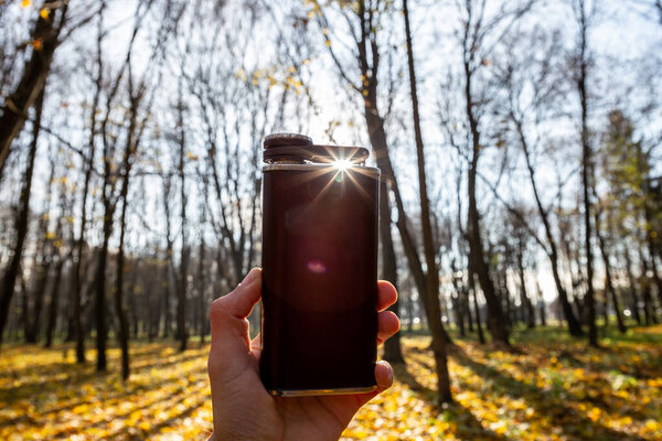 Metal flask for alcohol in the autumn forest. Autumn walks. Men's travel accessories.