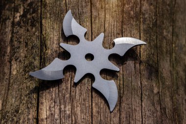 Shuriken (fırlatma yıldızı), geleneksel Japon Ninja soğuk silahı ahşap arka planda sıkışmış.