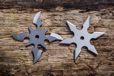 Shuriken (fırlatma yıldızı), geleneksel Japon Ninja soğuk silahı ahşap arka planda sıkışmış.