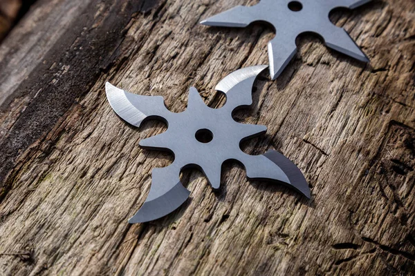 Shuriken (fırlatma yıldızı), geleneksel Japon Ninja soğuk silahı ahşap arka planda sıkışmış.
