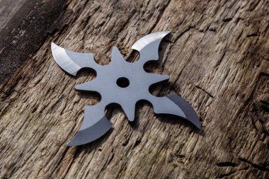 Shuriken (fırlatma yıldızı), geleneksel Japon Ninja soğuk silahı ahşap arka planda sıkışmış.