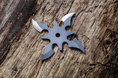 Shuriken (fırlatma yıldızı), geleneksel Japon Ninja soğuk silahı ahşap arka planda sıkışmış.