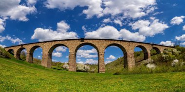 Old railway stone viaduct in the spring in sunny day. Ukraine  clipart