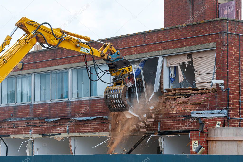 Demolition of an old building with a long reach machine hydraulic jaw. Regeneration of a space for new, modern building.