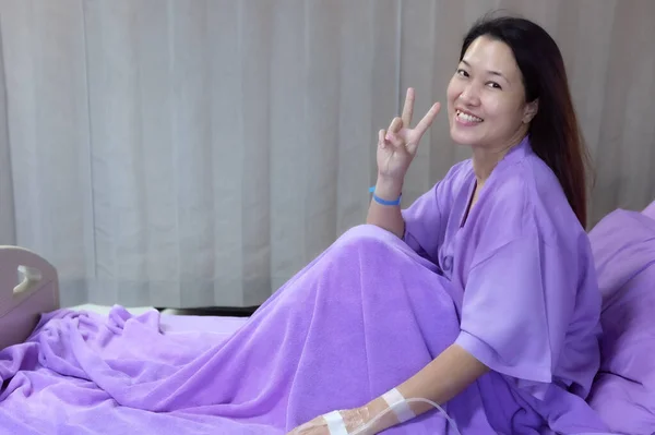 Asian female patient smiling and showing encouragement. Patients feel happy and comfortable when they are treated by hospitalization in the hospital room. Medical health care concept