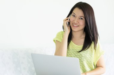 Dizüstü bilgisayar ve akıllı telefon kullanan kadın.