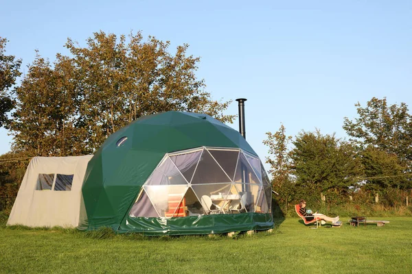 Lit up dome tent in a glamping site. Wales, UK