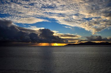 Praslin adası üzerinde günbatımının yüksek açılı görüntüsü canlı gökyüzü ve yansımalı okyanus.