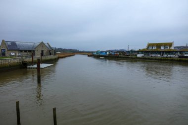 Nehir İngilizleri, bulutlu ve binalı sisli bir yağmur gününde. West Bay, Dorset, İngiltere.