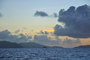 Deniz üzerinde harika bir gün batımı ve gölgede bir ada.