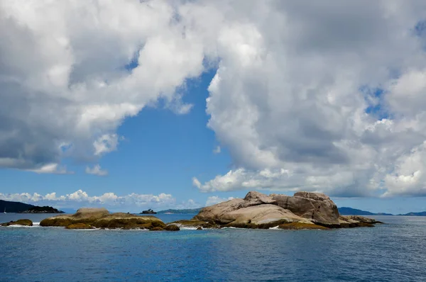 Outcropping rock famous for scuba diving in the Indian Ocean part of the Petit Soeur or Little Sister island on a sunny day with clouds.