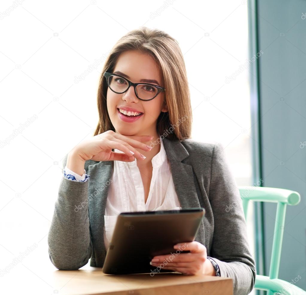 Happy businesswoman sitting  in office with laptop on white