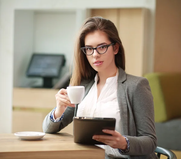 Jovem mulher de negócios com uma xícara de café trabalhando no escritório — Fotografia de Stock