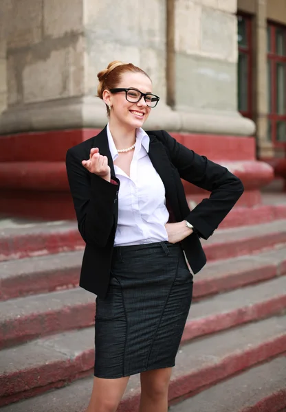 Cheerful student girl pointing a finger on university background — Stock Photo, Image