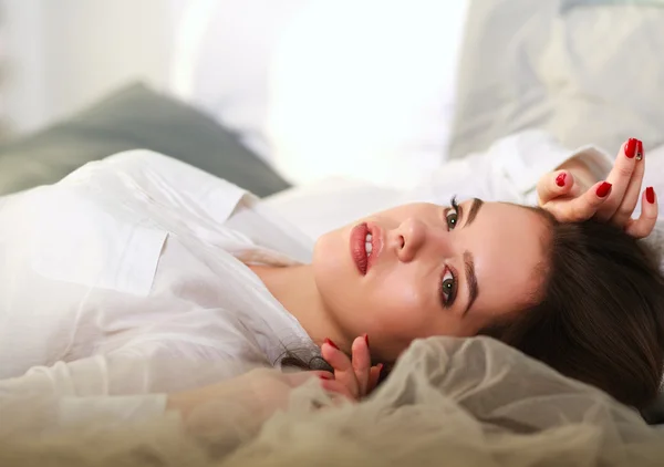 Όμορφη στοχαστικό κοπέλα ξαπλωμένη στο κρεβάτι σε φόντο του ήλιου — Φωτογραφία Αρχείου