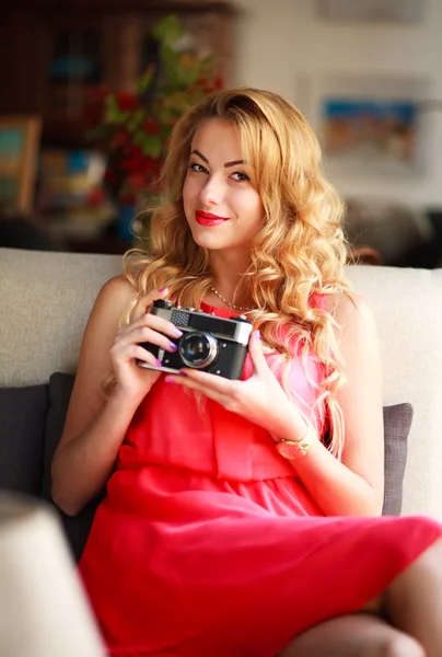 Mujer sonriente en vestido con cámara retro, en el sofá en casa —  Fotos de Stock