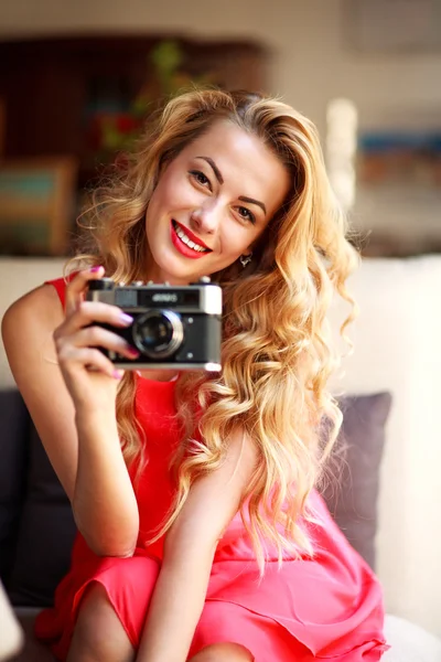 Mujer sonriente en vestido con cámara retro, en el sofá en casa —  Fotos de Stock