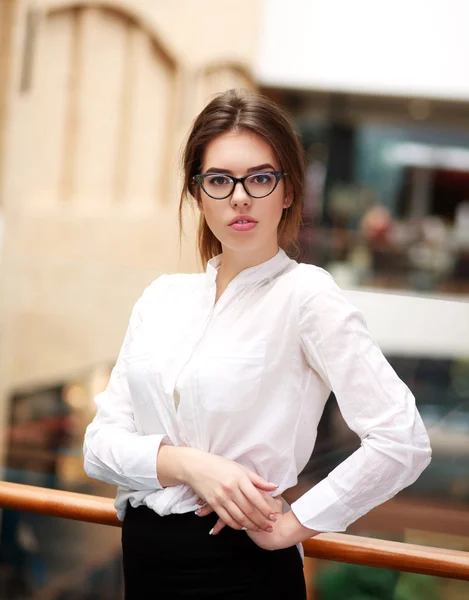 Joven mujer de negocios en gafas posando mientras está de pie en interiores — Foto de Stock