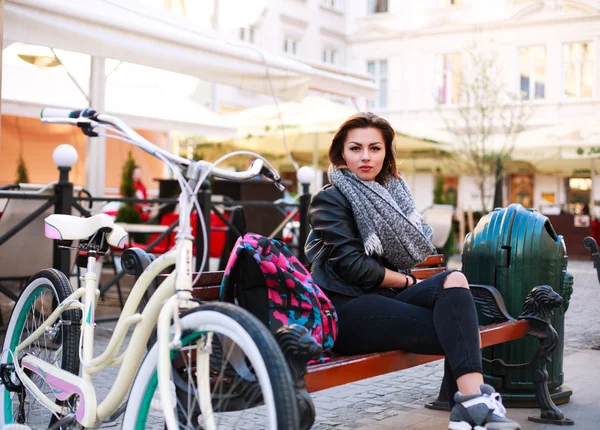 Девушка с винтажным велосипедом сидит на улице старого города — стоковое фото