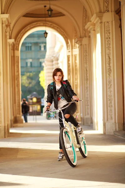 年轻的女子在日落古城的老式自行车 — 图库照片