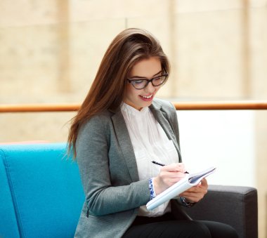 Neşeli kız öğrenci not defterinde kapalı yazma