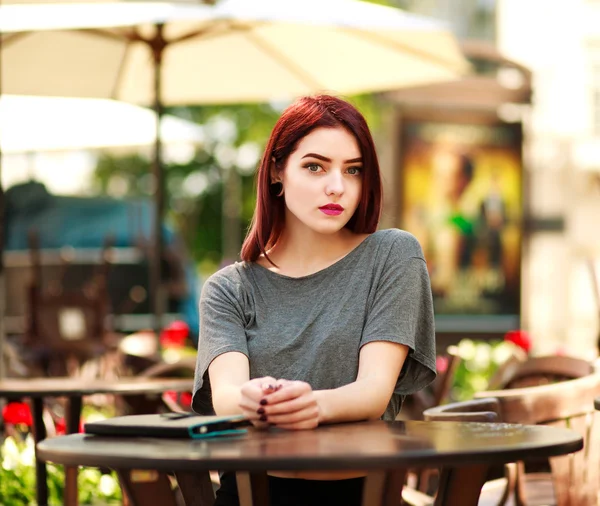 Hermosa chica en la mesa en el café de verano de la ciudad con la tableta —  Fotos de Stock