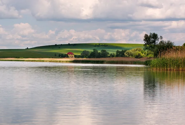 Paisaje tranquilo del lago en el pueblo bajo el cielo azul — Foto de Stock