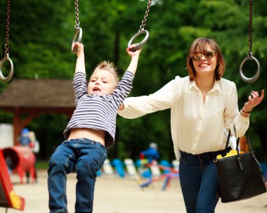 Salıncak Bahçesi yaz parkta oynayan çocuk ile anne