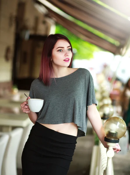 Stilvolle Brünette mit einer Tasse Kaffee auf dem Hintergrund des Sommercafés — Stockfoto