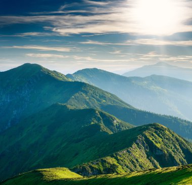 Güneşli gökyüzü arka planda yeşil ağaçlar dağ kaplı