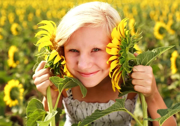 Happy smiling teen girl playing with sunflower in field — Stock Photo, Image