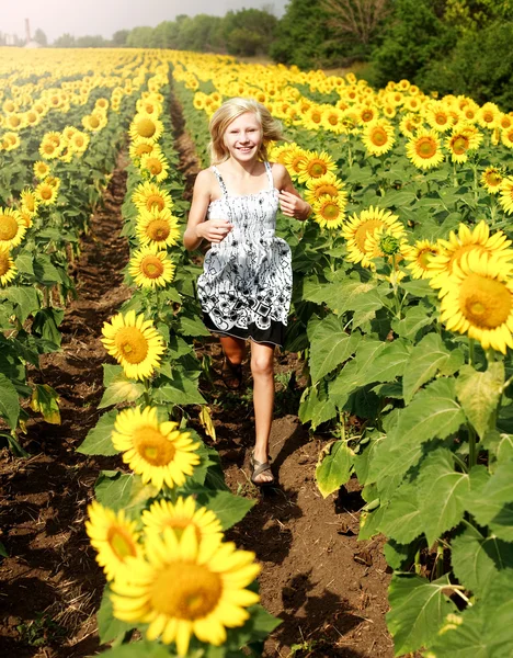 Sorridente ragazza adolescente felice corre nel campo dei girasoli — Foto Stock