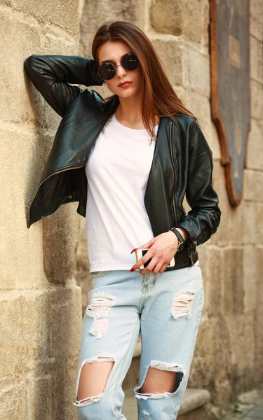 20世纪90年代流行复古风格的年轻女孩皮夹克和牛仔裤在古城的街上 — 图库照片