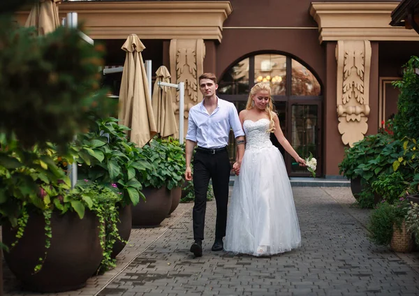 幸せなカップルで恋に一緒に彼らの結婚式の日に咲く緑の庭を散歩 — ストック写真